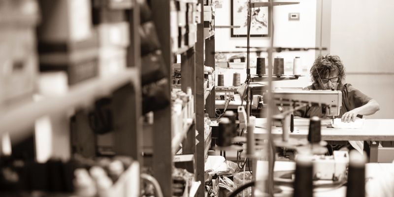 Skilled artisan working at industrial sewing machine, demonstrating professional manufacturing capabilities